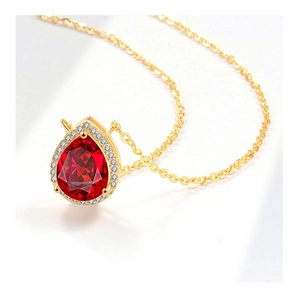Macro shot of gold plated water drop necklace with a red pear-shaped stone and zircons