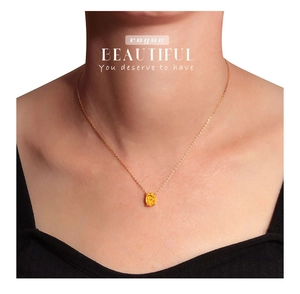 Close-up of elegant gold necklace with a vibrant oval yellow gemstone worn by a model
