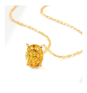 Macro shot of an elegant gold necklace featuring an oval yellow gemstone in a 4-claw setting