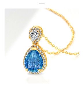 Close-up of golden necklace featuring a pear-cut blue sapphire pendant with diamond accents