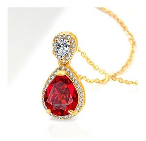 Close-up of gold pear-shaped necklace with vibrant red gemstone and zircon halo