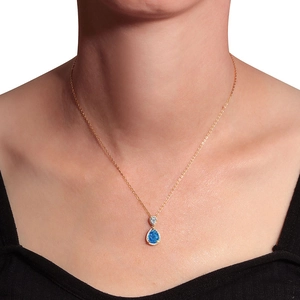 Elegant gold teardrop necklace with blue opal pendant and diamond halo on female neck