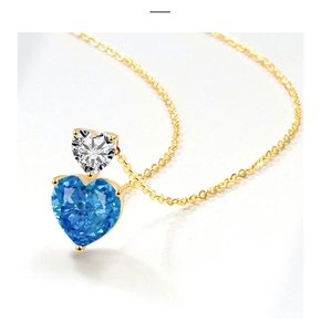 Macro shot of gold double heart pendant featuring sea blue and clear zircon stones