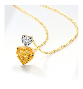 Close-up of double heart pendant necklace with white and yellow gemstones on gold chain