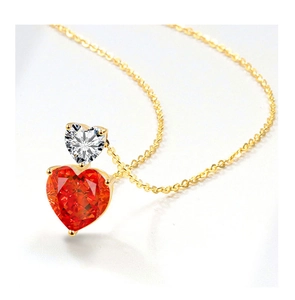 Macro shot of gold necklace with red heart-shaped gemstone and white cubic zirconia pendants