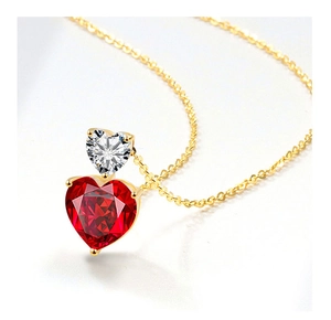 Macro shot of double heart pendant with red crystal and clear zircon on a gold chain