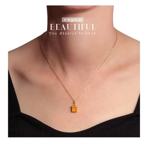 Close-up of elegant gold necklace featuring a rectangular yellow gemstone pendant on model