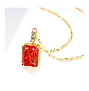 Macro shot of gold necklace with rectangular red stone pendant and small white crystals