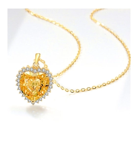 Makro-Detail eines herzförmigen gelben Edelsteinanhängers mit feiner Goldkette und Halo-Diamanten
