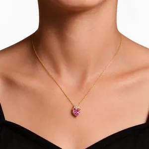 Close-up of a pink heart-shaped crystal pendant on a gold O-chain necklace on model