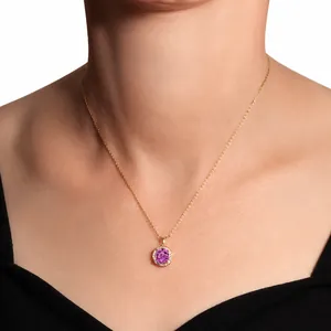 Golden pendant necklace with a purple round stone surrounded by pavé diamonds on a model