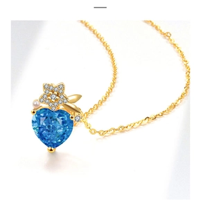 Close-up of golden necklace featuring a heart blue sapphire and micro-set diamond star