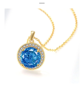 Macro shot of gold necklace featuring a round blue gemstone with a halo of white zircon