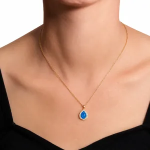 Close-up of gold necklace with blue teardrop stone and zircon details on model neck