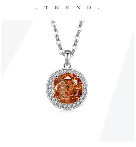 Macro shot of silver pendant necklace with orange gemstone and sparkling crystal halo