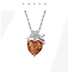 Detailed view of an orange heart pendant necklace with floral silver accents and pearl