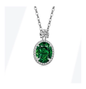 Détail macro d'un pendentif émeraude ovale avec chaîne en argent et monture pavée