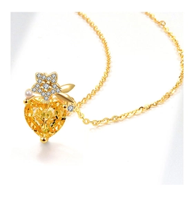 Detailed view of yellow heart gemstone necklace with gold leaf, pearl and star accents