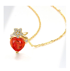 Detailed close-up of a golden heart necklace with red crystal, flower and pearl charm