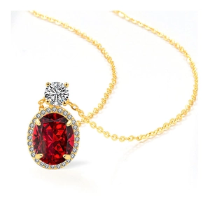 Détail macro d'un collier en or avec pendentif rubis ovale et accents de diamants blancs