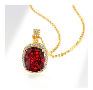 Gros plan du collier avec pendentif en pierre rouge coupe coussin et fine chaîne dorée