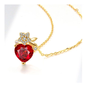 Macro shot of heart-shaped red ruby pendant with gold star detailing and a white pearl