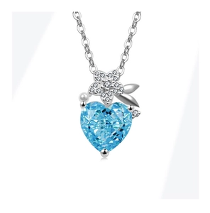 Detail view of silver necklace with heart-shaped light blue stone and floral metal accent