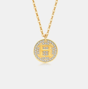 Detail van een goudkleurige ketting met H-letter hanger en sprankelende kristallen
