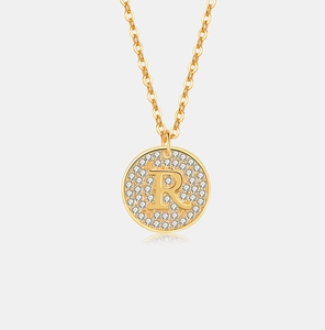 Macro-opname van de gouden ronde hanger met letter R en micro-pave witte zirkonia