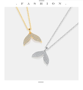Detailed close-up of gold and silver mermaid tail pendants with white zircon stones