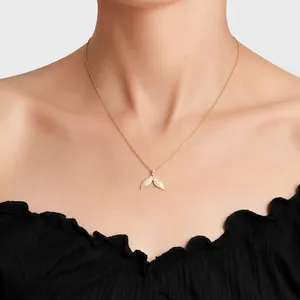 Close-up of a gold fish tail pendant necklace with sparkling white zircon stones on a model