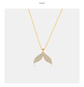 Close-up of golden mermaid tail necklace featuring micro-set diamonds on the fin