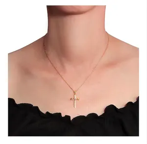 Close-up of golden cross necklace with white zircon stone worn by a female model