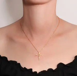 Close-up of gold cross pendant with heart detail and zircons on a delicate chain