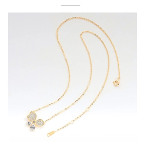 Macro-detail van een gouden vlinderhanger ketting met ingelegde stenen en O-ketting