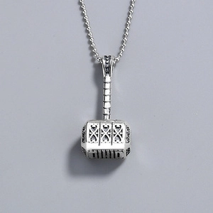 Close-up of vintage silver Mjolnir hammer pendant with intricate embossed carvings