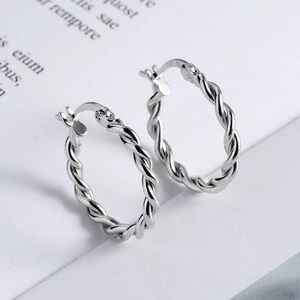 Minimalist 925 sterling silver hoop earrings with twisted metal texture on a white book