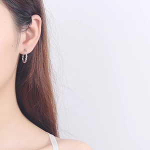 Minimalist 925 sterling silver twisted hoop earrings worn on a model with white background