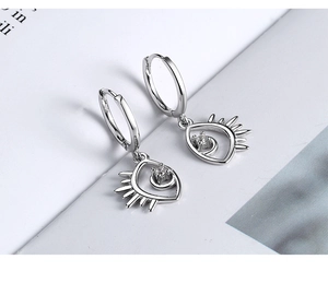 Detail of s925 silver evil eye earrings with sparkling cubic zirconia on open book