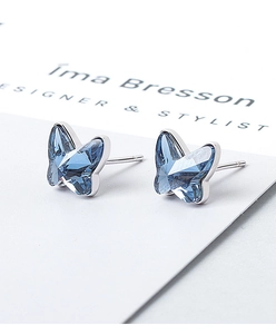 Macro shot of sparkling blue crystal butterfly stud earrings on a white designer card