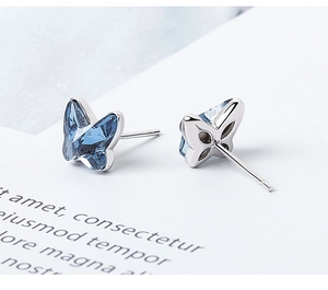 Macro shot of sky blue crystal butterfly stud earrings in silver minimalist setting