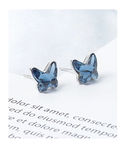 Macro shot of blue butterfly crystal stud earrings on white paper background