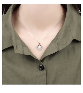 Macro shot of silver heart-shaped necklace with central white gemstone and halo crystals