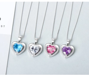 Detailed view of four heart-shaped crystal necklaces in blue, pink, purple, and clear