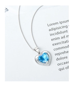 Close-up of heart-shaped blue gemstone necklace with halo cubic zirconia setting