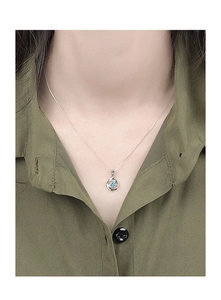Primer plano de collar de plata con colgante en espiral y circonita azul sobre una modelo