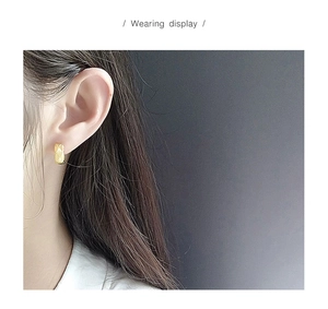 Detailed view of S925 silver quilted diamond pattern earrings in gold finish on ear