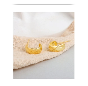 Detailed close-up of C-shaped golden earrings with elegant quilted pattern textures