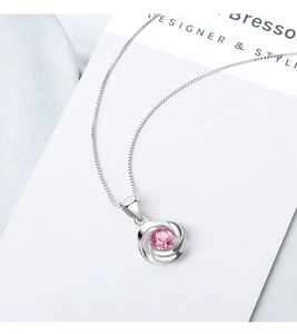 Detalle del colgante de rosa con circón rosa y cadena de caja de plata sobre raso azul