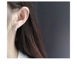 Close-up of S925 sterling silver hoop earrings with a quilted rhombus pattern on ear